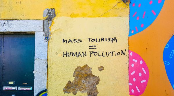 reisen ohne social media: eine bunte wand, an die jemand geschrieben hat: mass tourism = social pollution