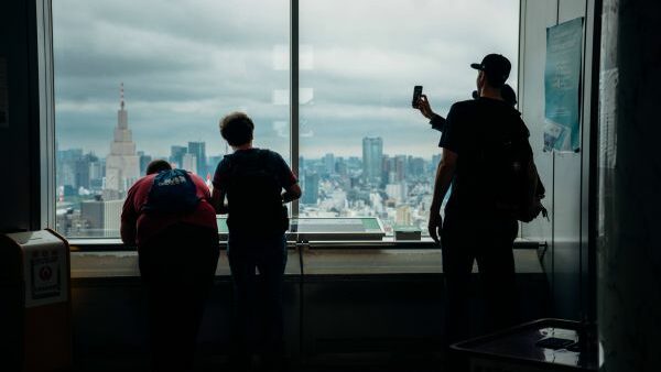 reisen ohne social media: menschen betrachten eine stadt von oben durch eine scheibe, zwei von ihnen machen ein selfie